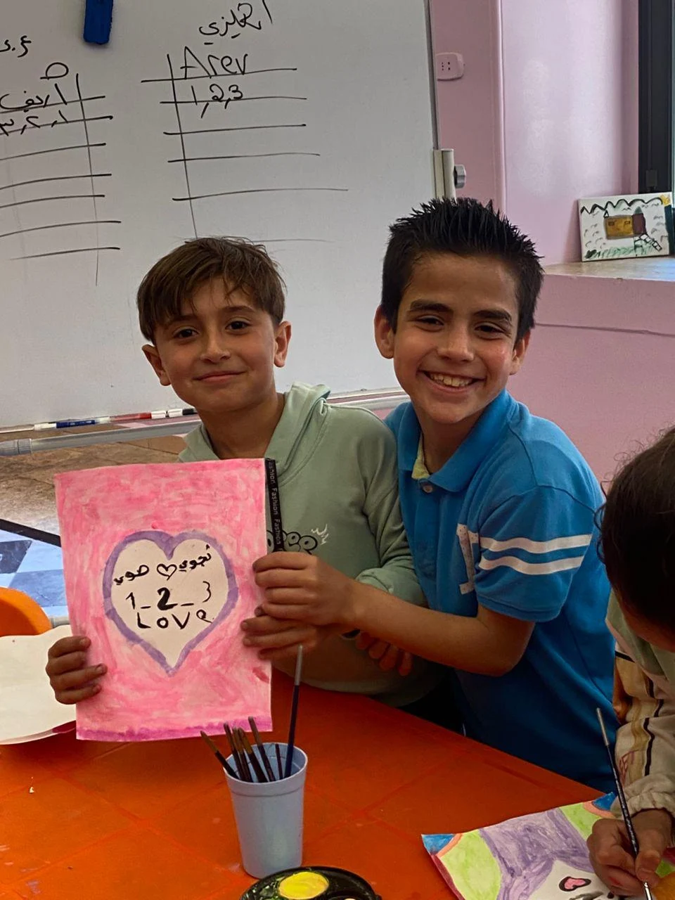 Two children showing a drawing with the word love.